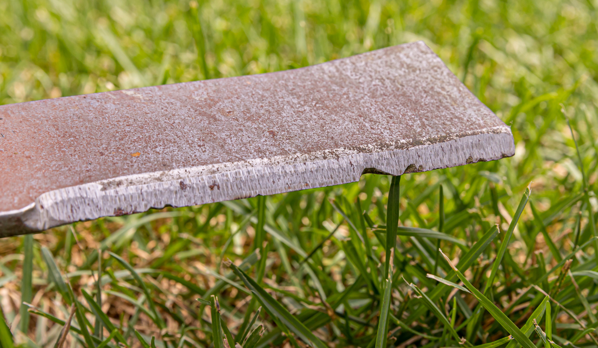 Close up of a nicked and dinged rotary mower blade 