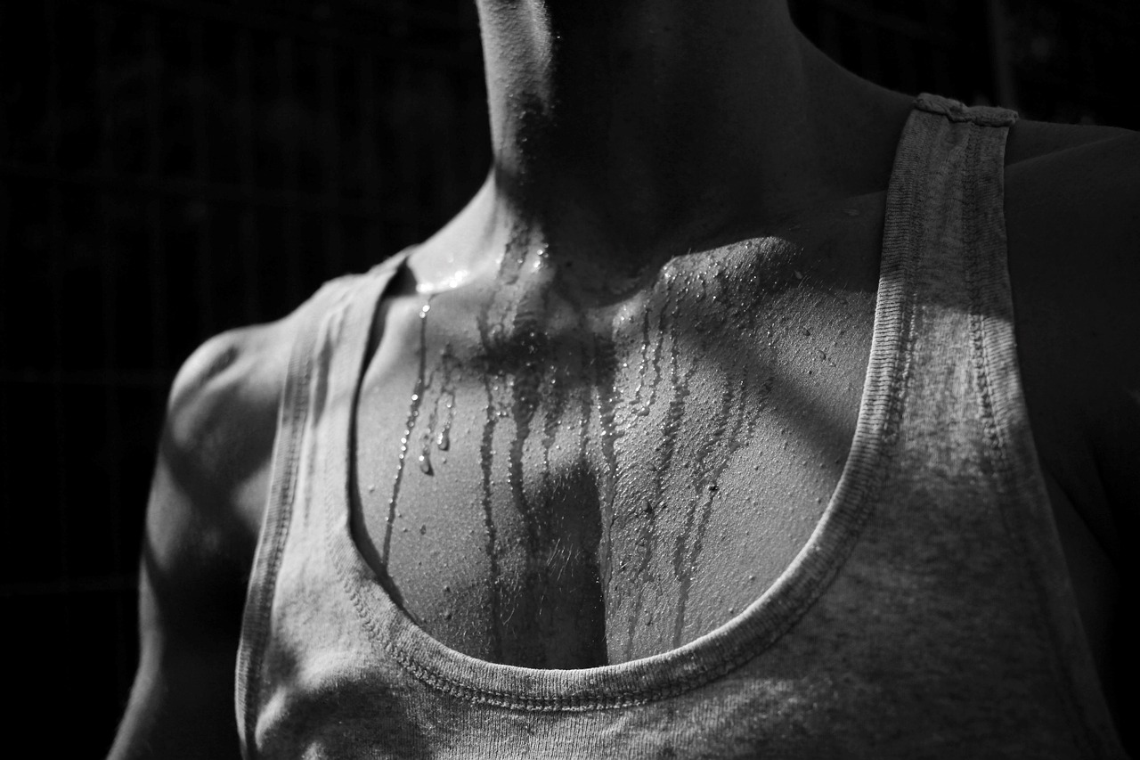 An image of the sweating chest of a human in a tank top after a workout risking dehydration.