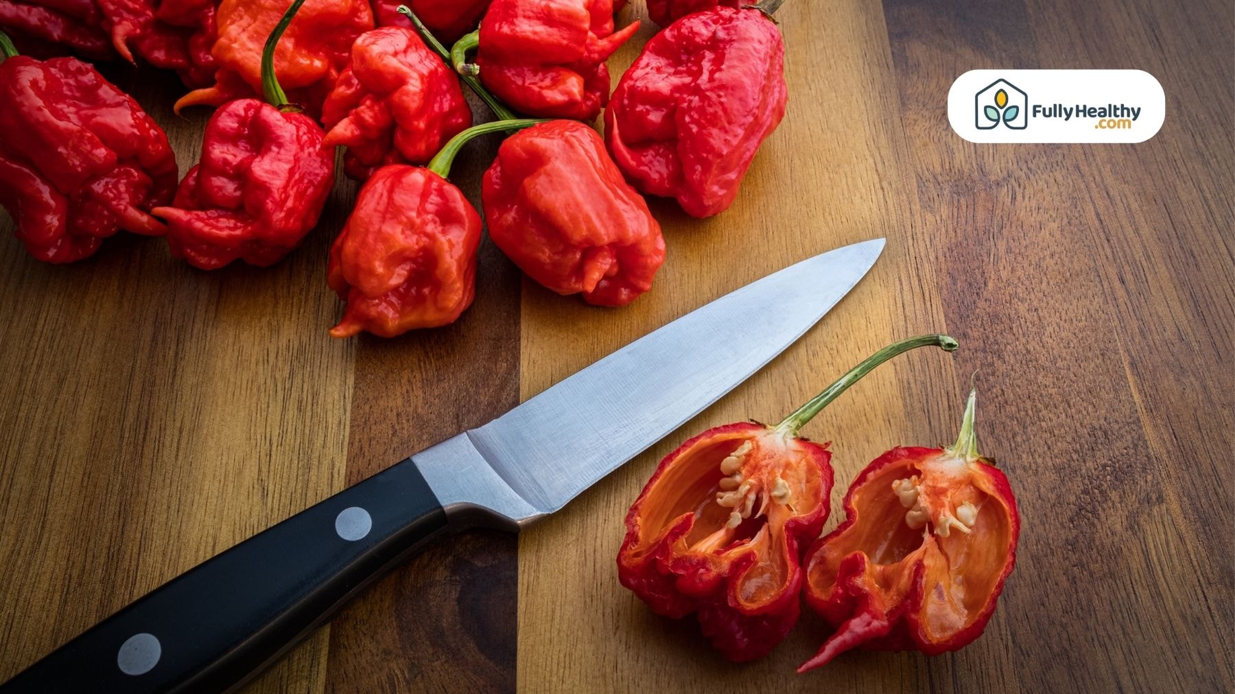 Sliced Carolina Reapers with seeds and a knife on a wooden board