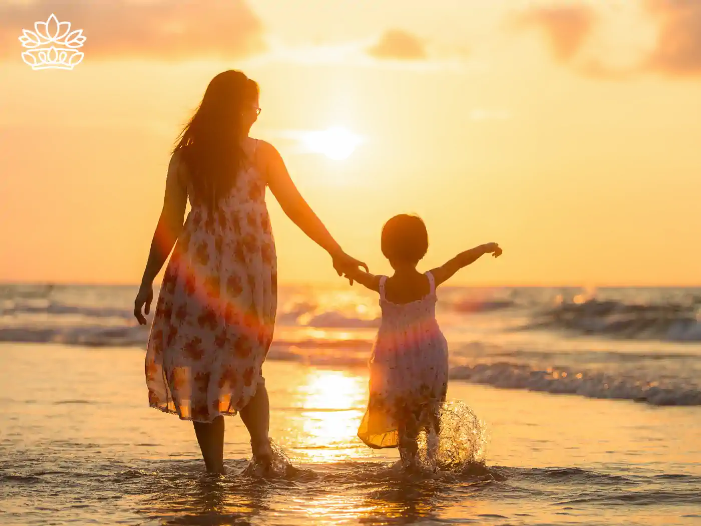 A mother and daughter holding hands and walking on the beach at sunset. Fabulous Flowers and Gifts. Mother's Day Flowers.