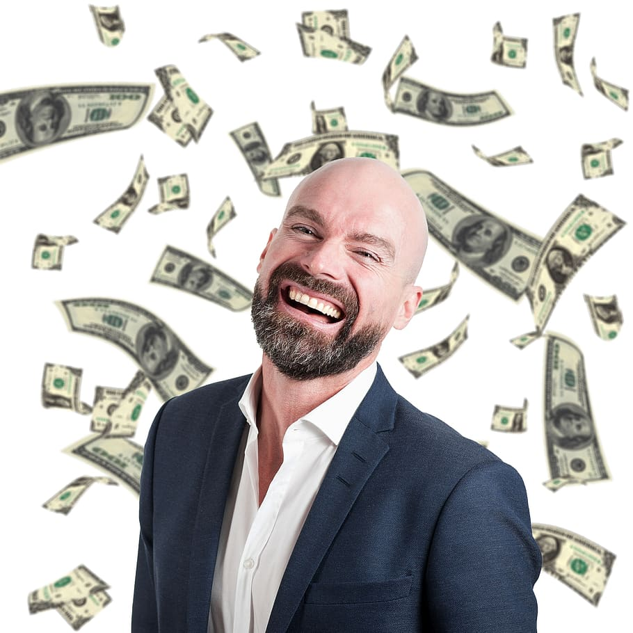 A man holding a stack of cash, smiling, with a junk car in the background