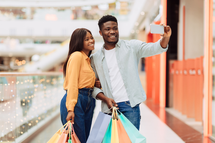 Happy African American couple holding shopping bags in a mall.