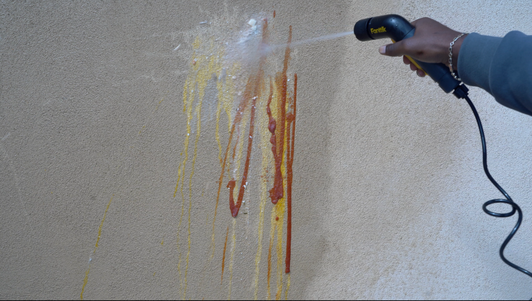 Fanttik NB10 Nano Portable Pressure Washer on wall with stubborn grime