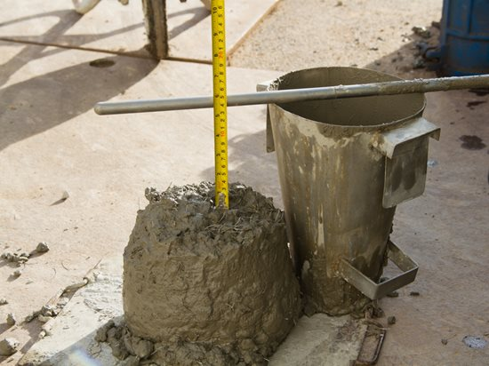 A slump tester being used to measure the consistency of concrete during construction.