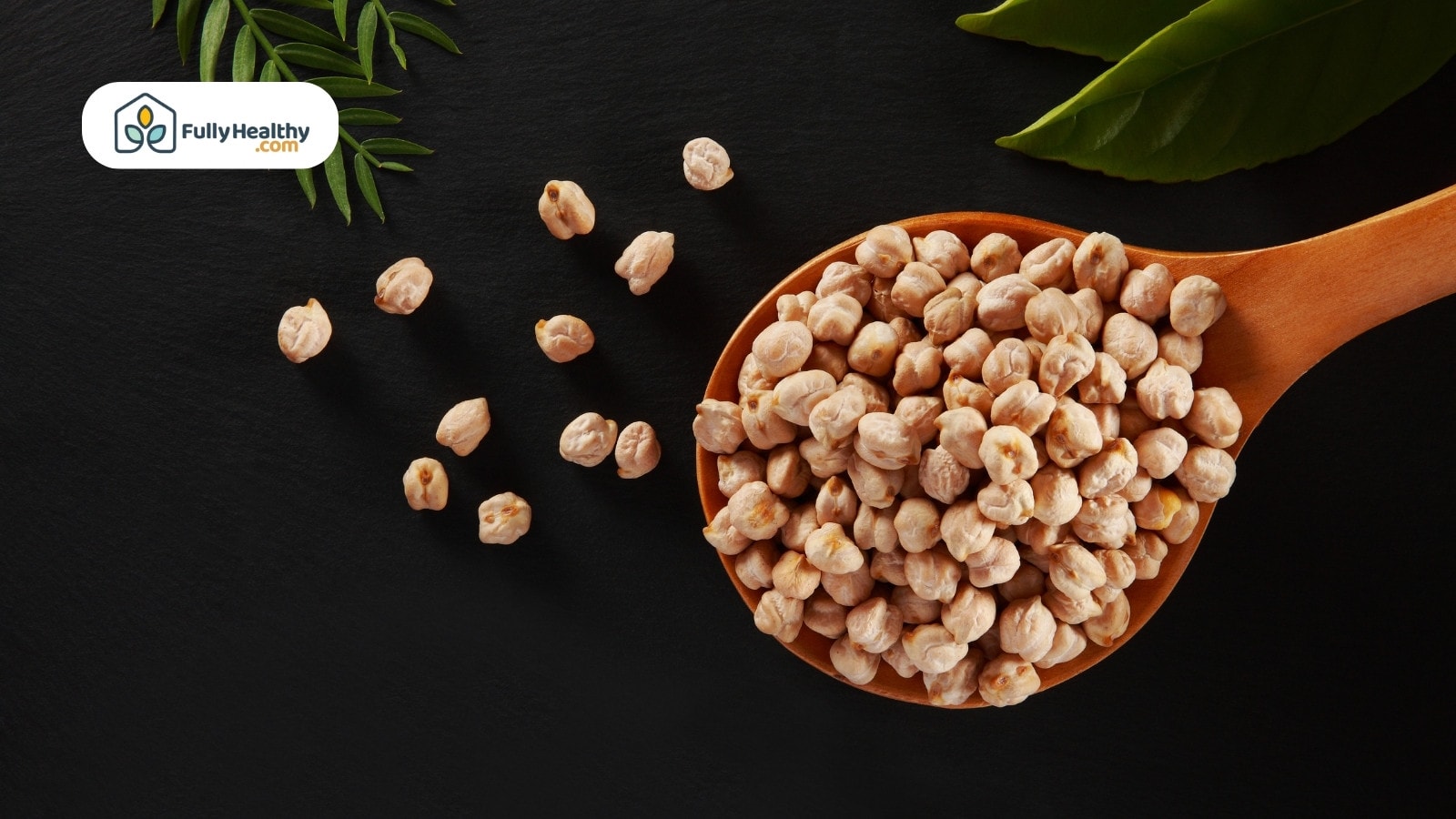 Wooden spoon filled with raw chickpeas scattered on black background