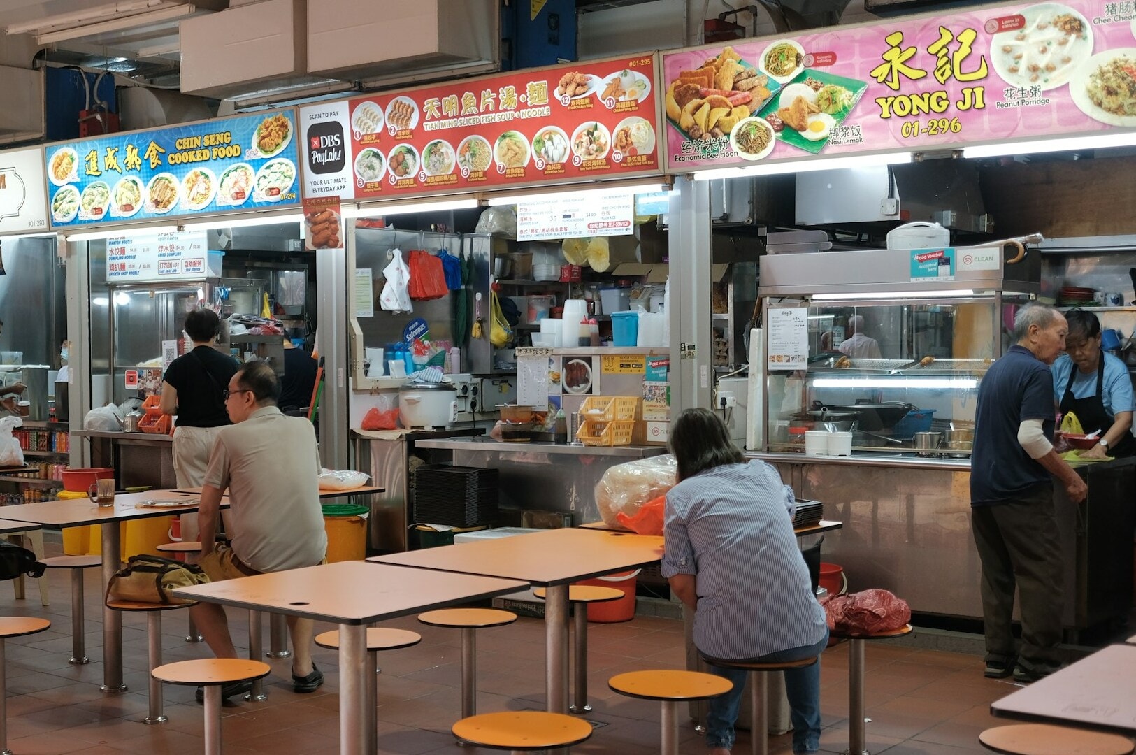 A bustling Singapore Hawkers restaurant filled with numerous tables and chairs for diners.
