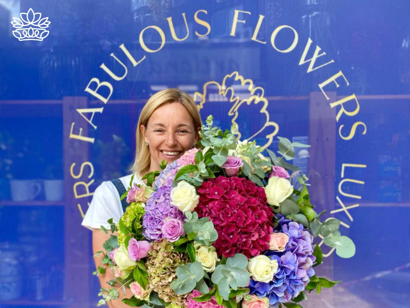 A smiling woman presenting a large and luxurious bouquet s.
