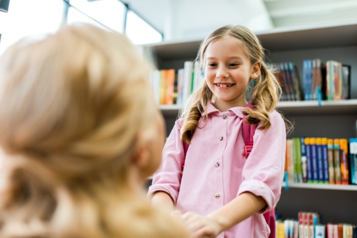 A happy student is excited to meet a real-life children's book author/illustrator in the school library.