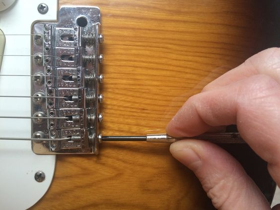 setting the intonation of a guitar with a small screwdriver