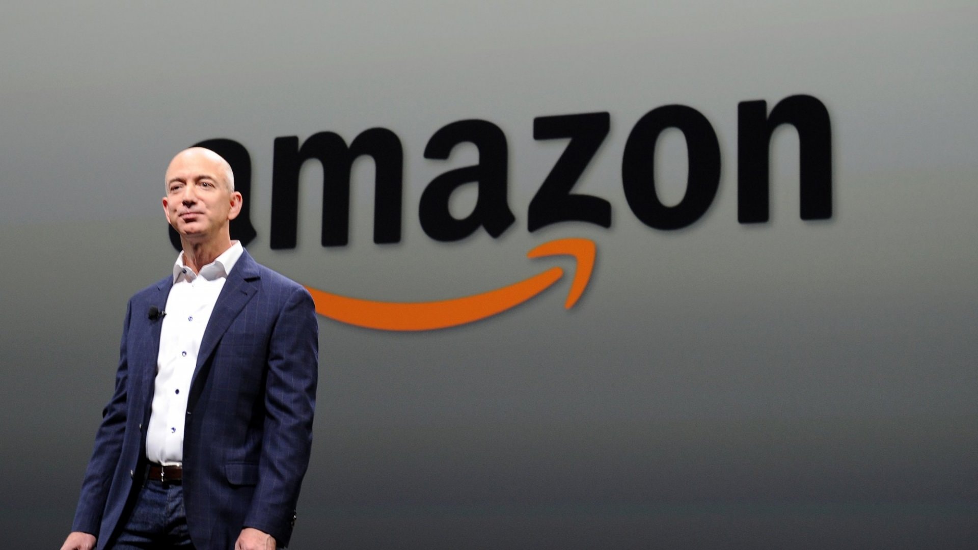 An image of Jeff Bezos standing in front of an Amazon sign. 