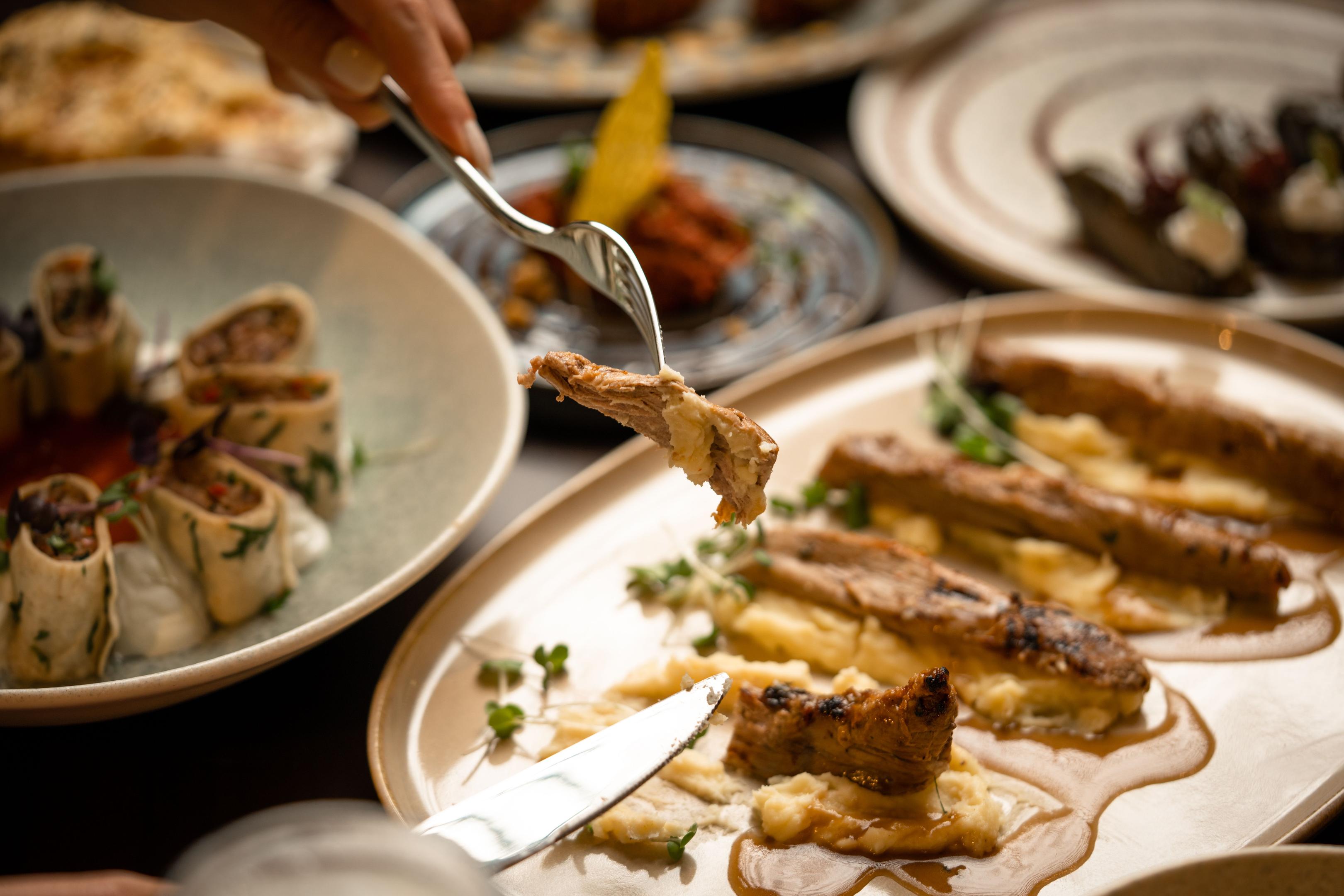 An overhead view showcases an array of beautifully plated dishes on a rustic wooden table, highlighting the restaurant's commitment to high-quality food presentation. This enticing display not only enhances customer satisfaction but also serves as an effective marketing strategy to attract potential customers and encourage repeat business.