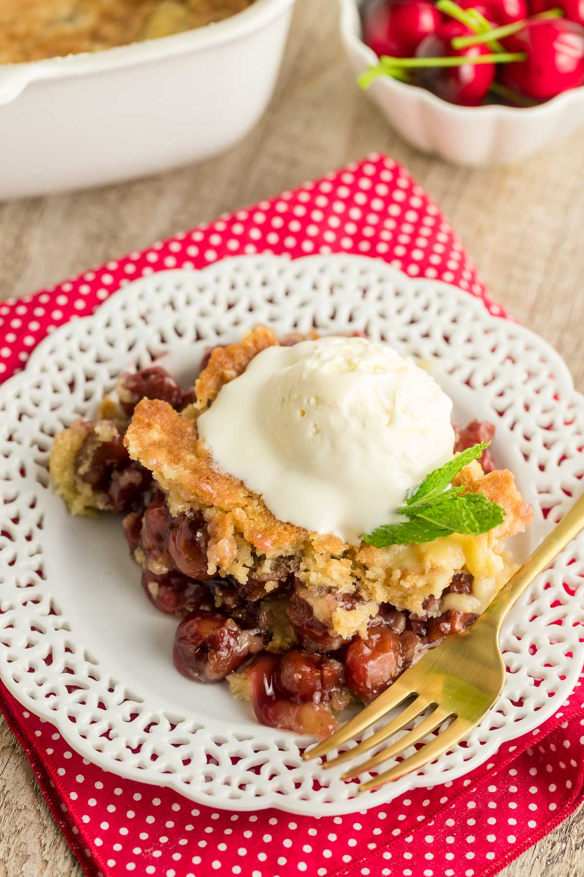 cherry dump cake topped with ice cream on a plate with a fork 