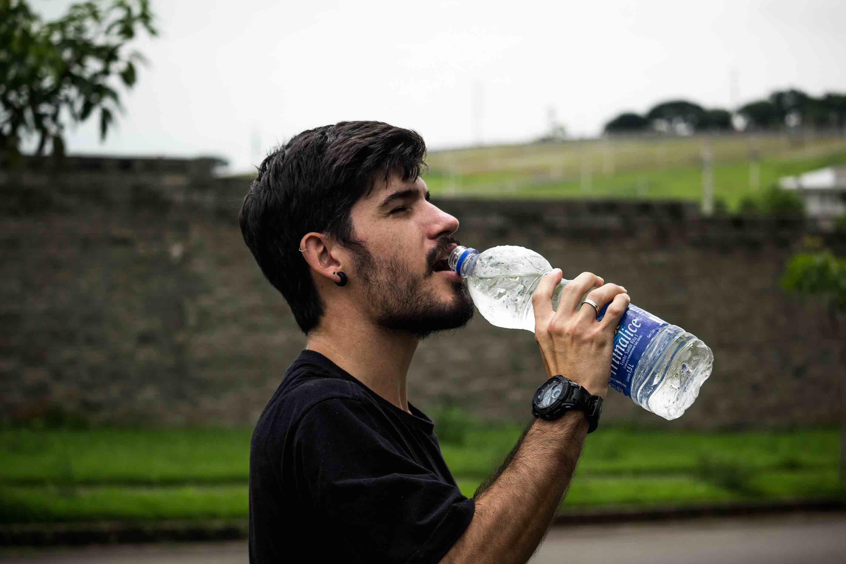 Junger Mann trinkt eine Flasche Wasser