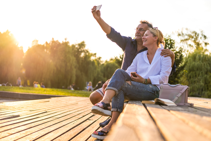 Cheerful blond couple sitting outside and snapping a selfie.