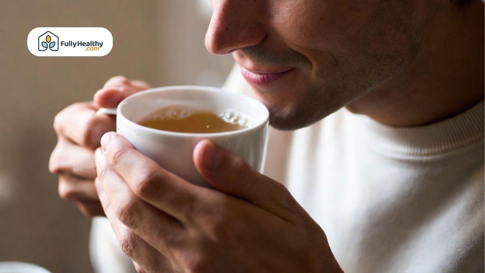 Person holding a cup of hot broth and gently smelling it.