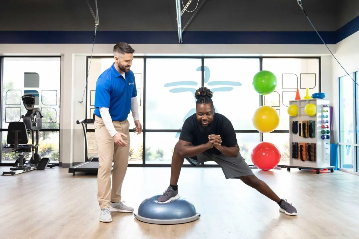 Athlete doing balance training on a BOSU ball with the best sports physical therapist coaching form