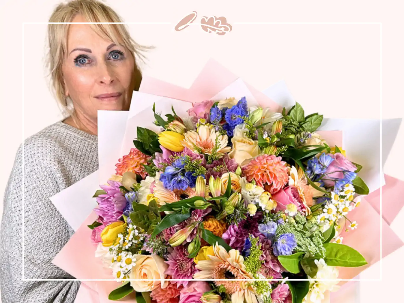 Female florist holding a vibrant bouquet of mixed flowers, featuring pinks, yellows, and greens, against a light background - Fabulous Flowers and Gifts