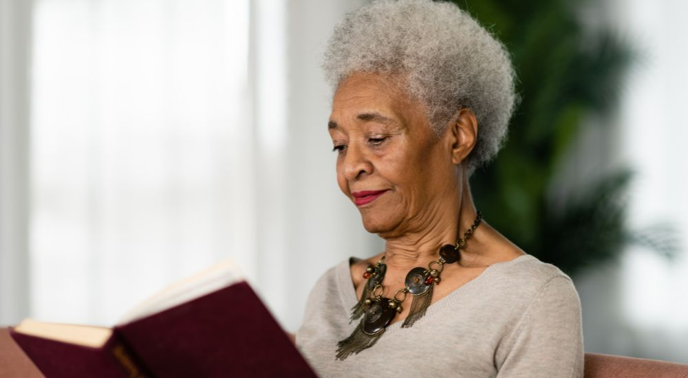 Senior citizen reading a book at home while aging in place