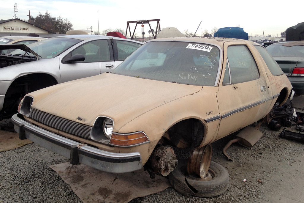 A rusty junk car with missing wheels