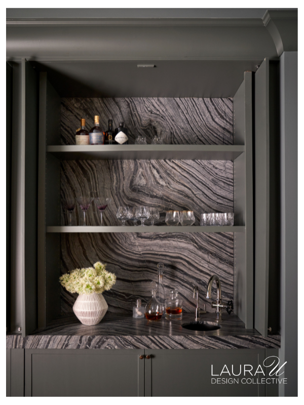 Custom wet bar with veined stone, dark cabinetry, and open shelving inside the Huntwick Forest wine cellar.