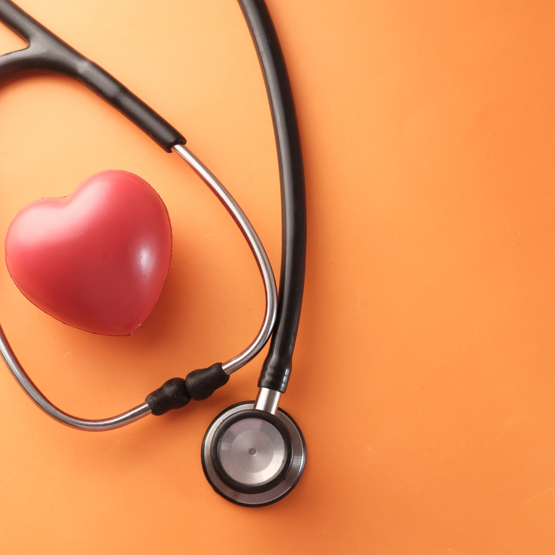 Stethoscope and red plastic heart on an orange background 