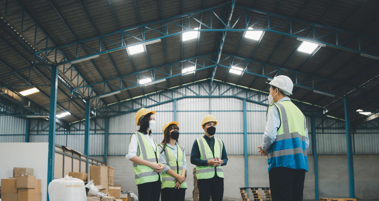 Warehouse manager in hard hat talking to staff
