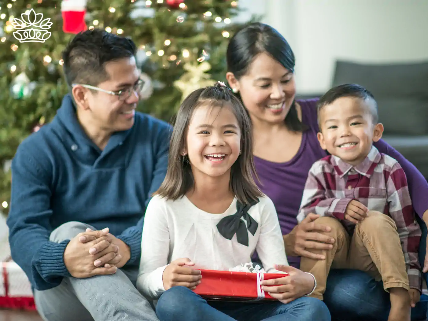 A happy family exchanging gifts by the Christmas tree, illustrating festive joy provided by Nationwide Gift Delivery. Fabulous Flowers and Gifts - Nationwide Gift Delivery