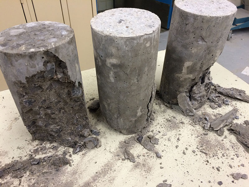 Concrete cylinder being tested for compressive strength