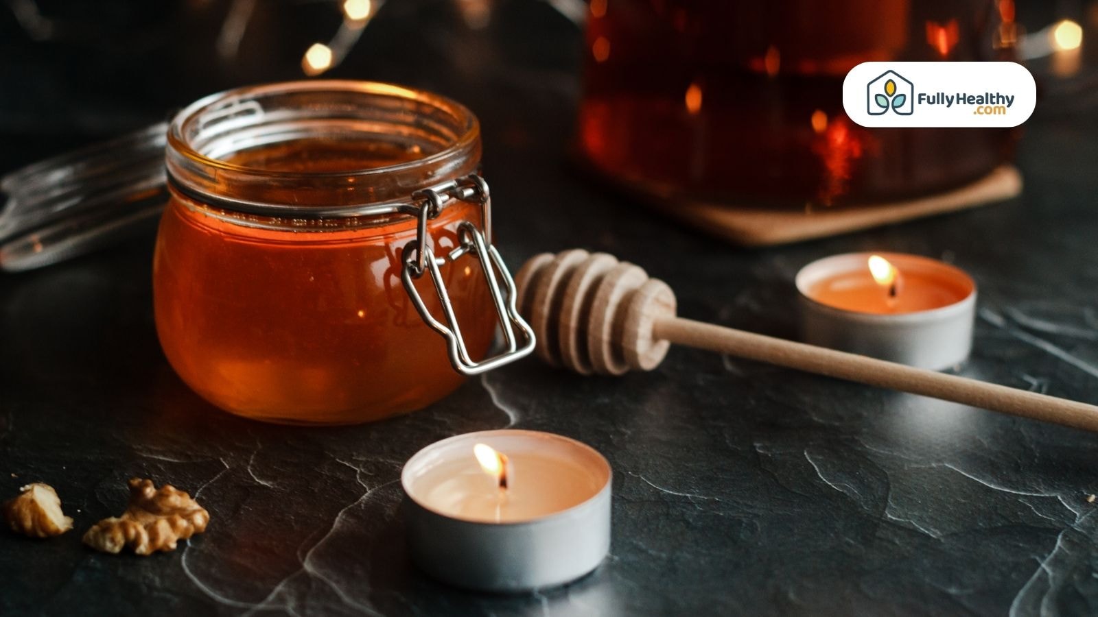 Glass jar of honey with candles on table