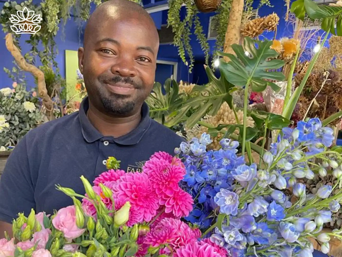 Smiling gentleman presenting a vibrant bouquet with pink roses, magenta dahlias, and blue delphiniums, available at Fabulous Flowers and Gifts.