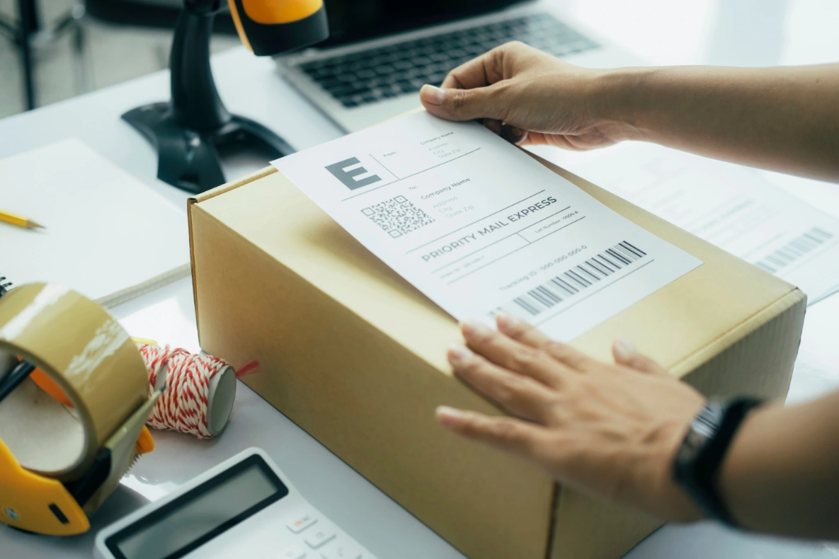 A person is putting a shipping label on a cardboard box, showing what suppliers for dropshipping do everyday.