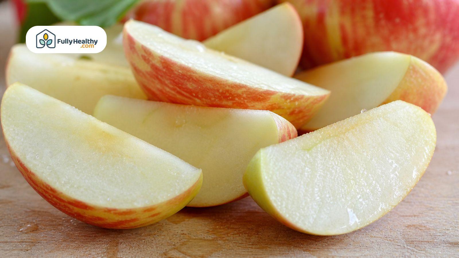 Freshly cut apple slices with juicy texture and minimal browning on a wooden board.