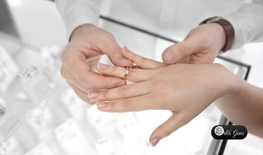 Jeweler assisting a customer trying on a princess cut diamond engagement ring, exemplifying personalized service to choose the perfect princess cut diamond, by Orbis Gems.
