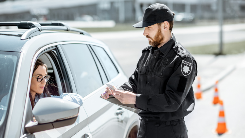 A policeman is checking the car window tint film percentage.