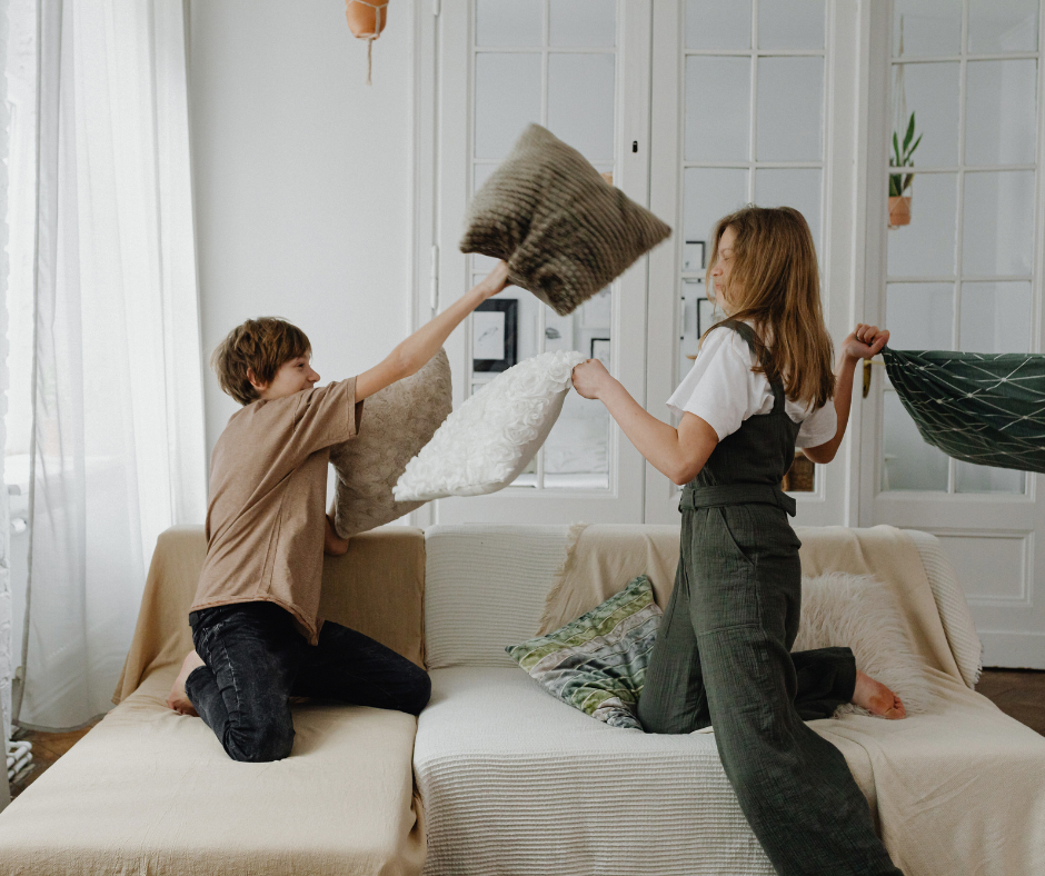 kids pillow-fighting on a couch