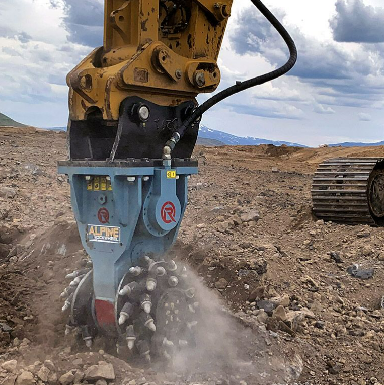 Excavator using a Rockwheel attachment to grind and cut through rocky soil Excavator using a Rockwheel attachment to grind and cut through rocky soil