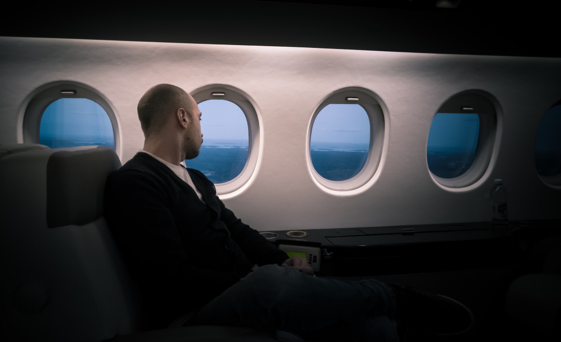 A man sitting in the first class type of flights and looking through the airplane window.