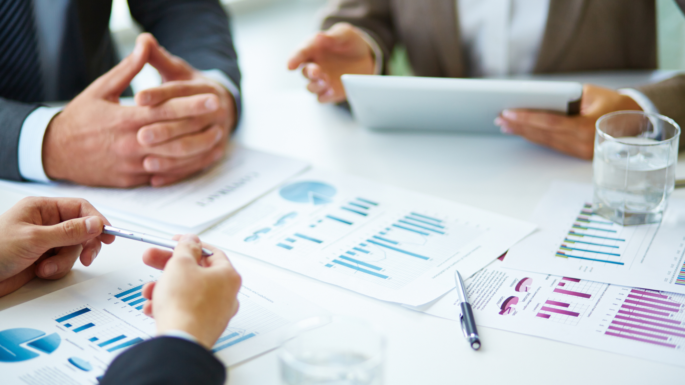Close-up of business professionals analyzing financial graphs and charts during a meeting, showcasing corporate strategy and data analysis.