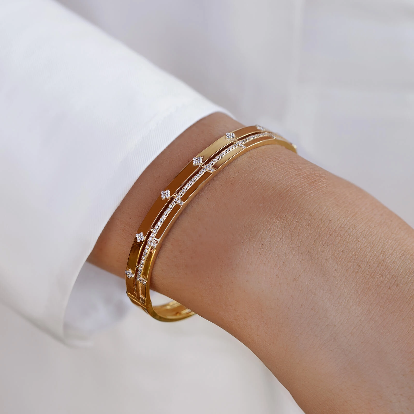 "A woman showcasing a luxurious gold bracelet on her wrist, styled for a casual occasion. The bracelet measure sleek design elevates her look, offering a glimpse of elegance and timeless wrap."