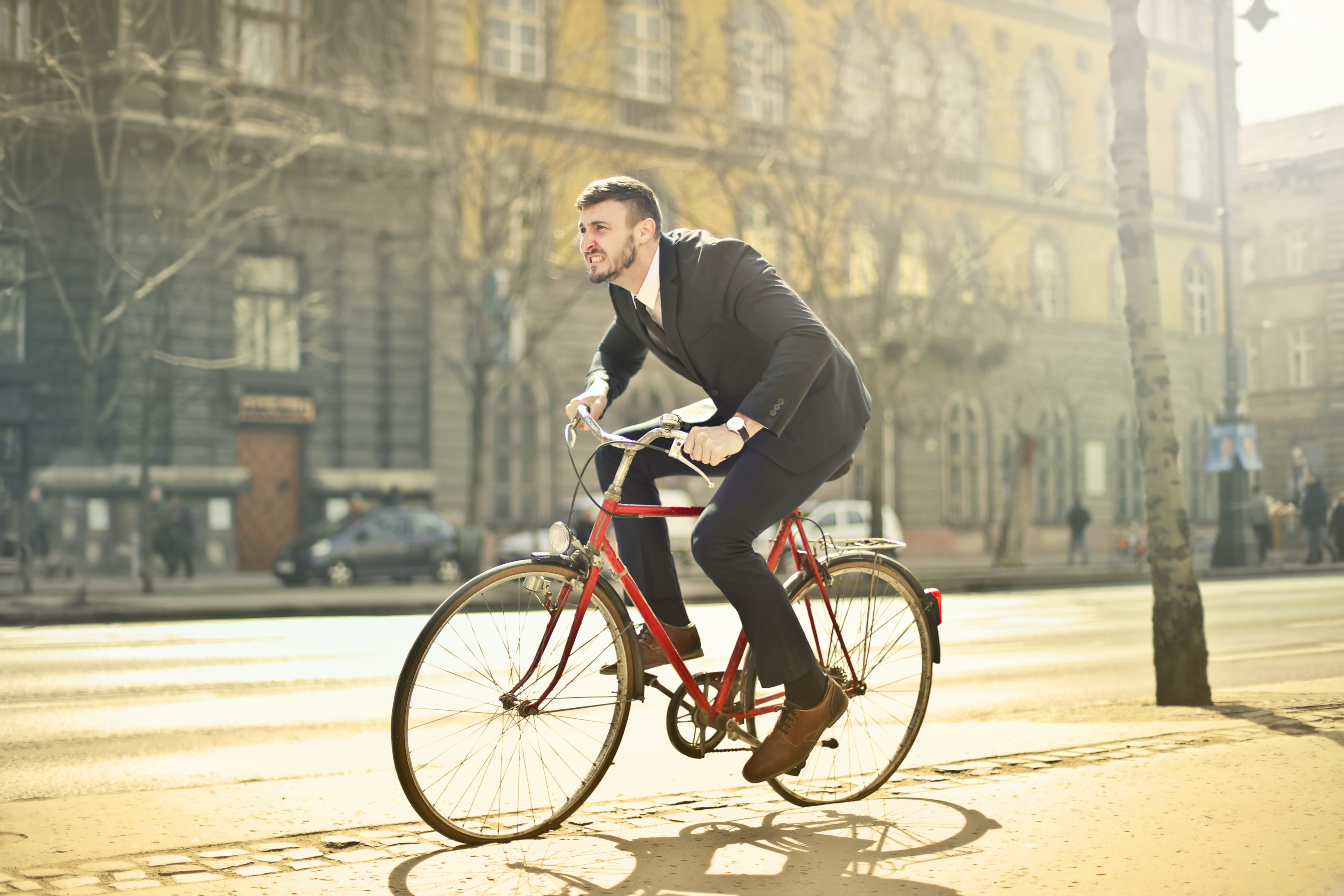 Ciclista vestido de terno e gravata, pedalando no meio da cidade