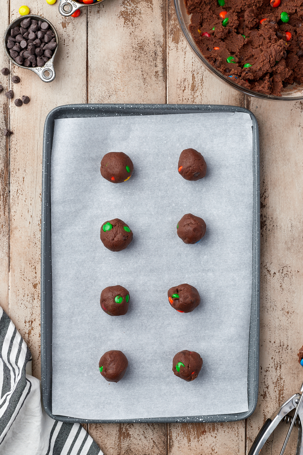 chocolate cookie dough balls scooped onto parchment paper on baking sheet
