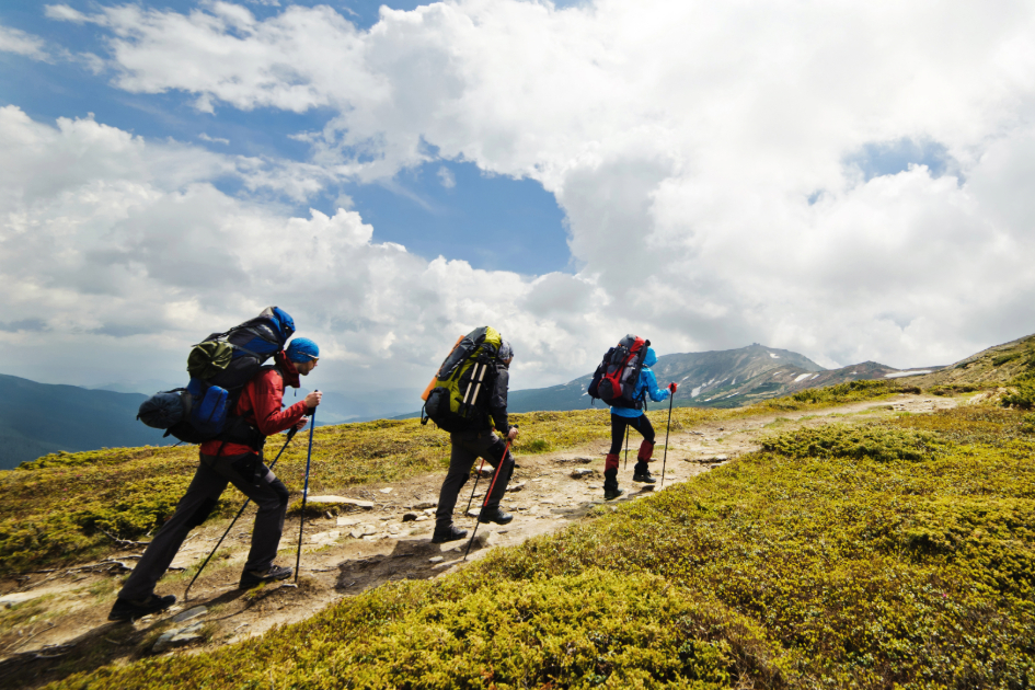 Hiker in rugged hiking pants climbing a rocky slope with a backpack, showing durability and fit for tough terrains.