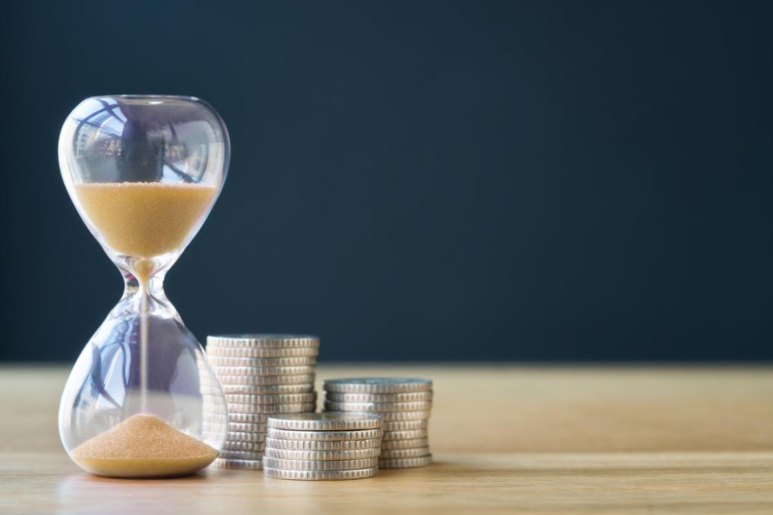 Hourglass and stacked coins representing time and financial savings when selling a business without a broker