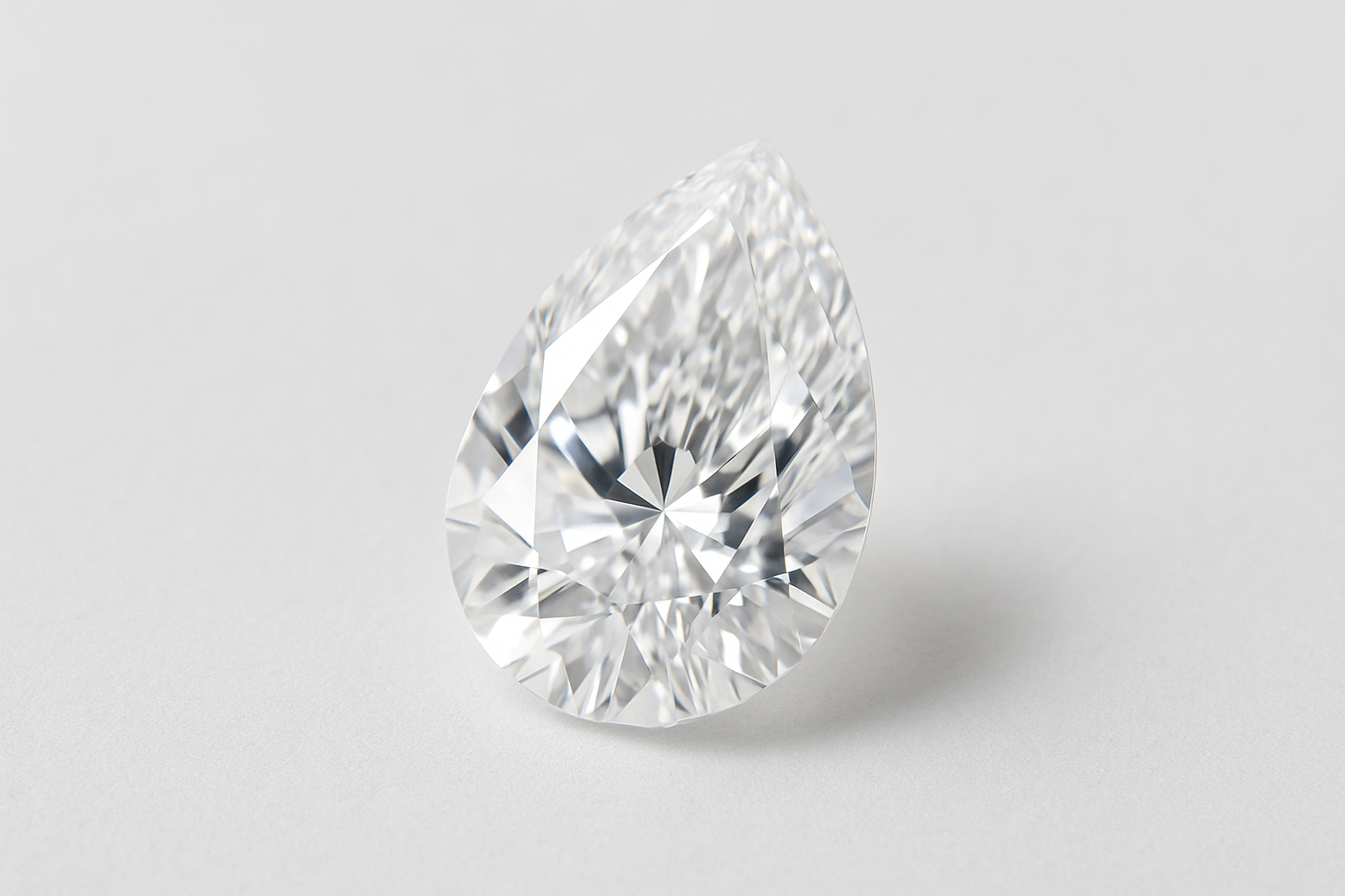 lāses formas (pear shape) dimants uz balta vai gaiši pelēka fona, ar maigu dabisku apgaismojumu, kas izceļ tā mirdzumu un šķautnes