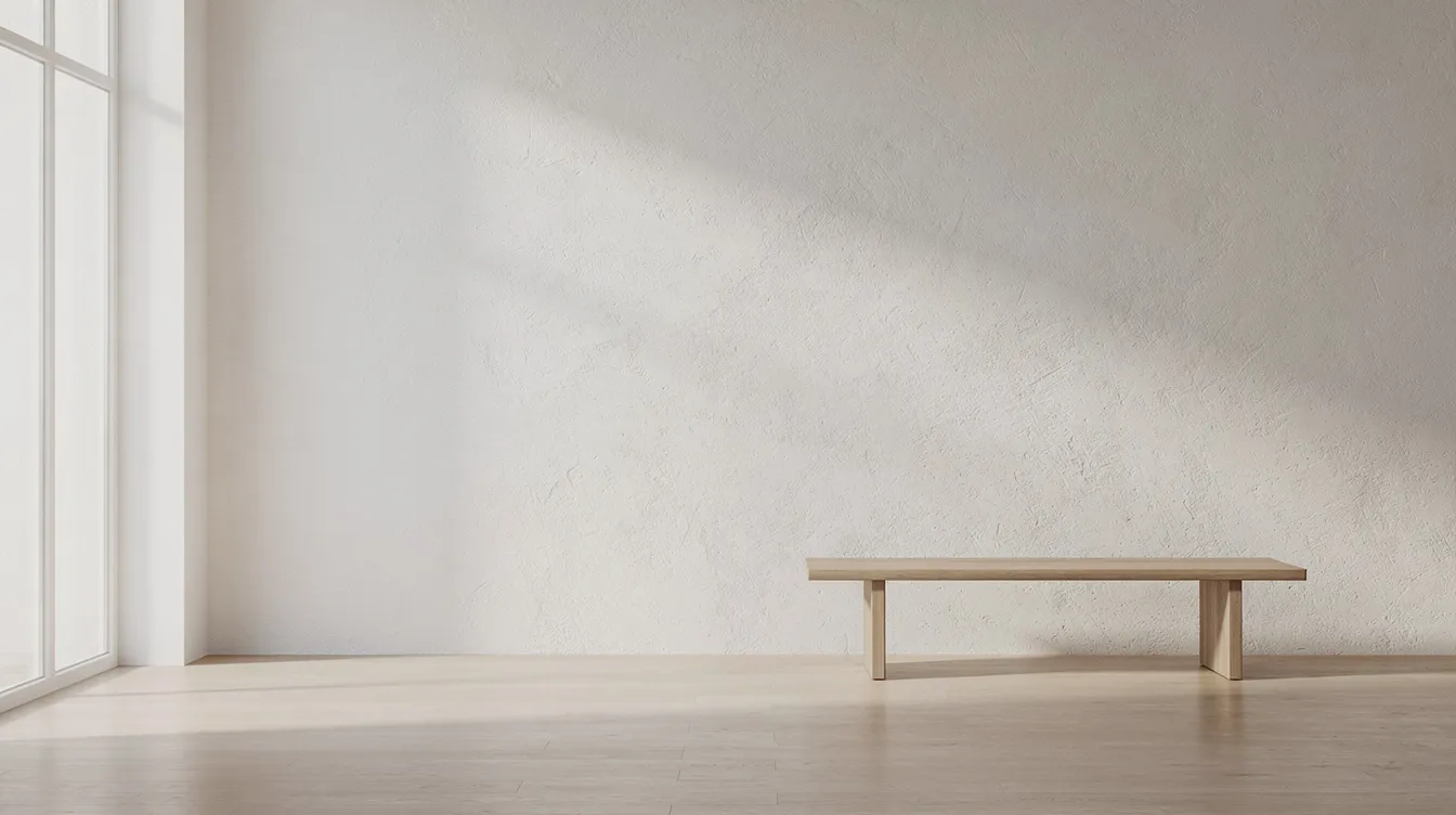The image depicts a minimal interior room featuring a soft matte plaster wall that reflects natural light, creating a serene atmosphere. The subtle texture of the wall enhances the space's elegance, showcasing the beauty of marmorino and venetian plaster finishes.