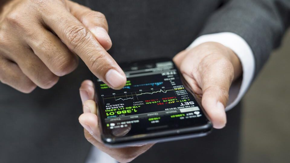 Man's hands holding smartphone displaying investment information