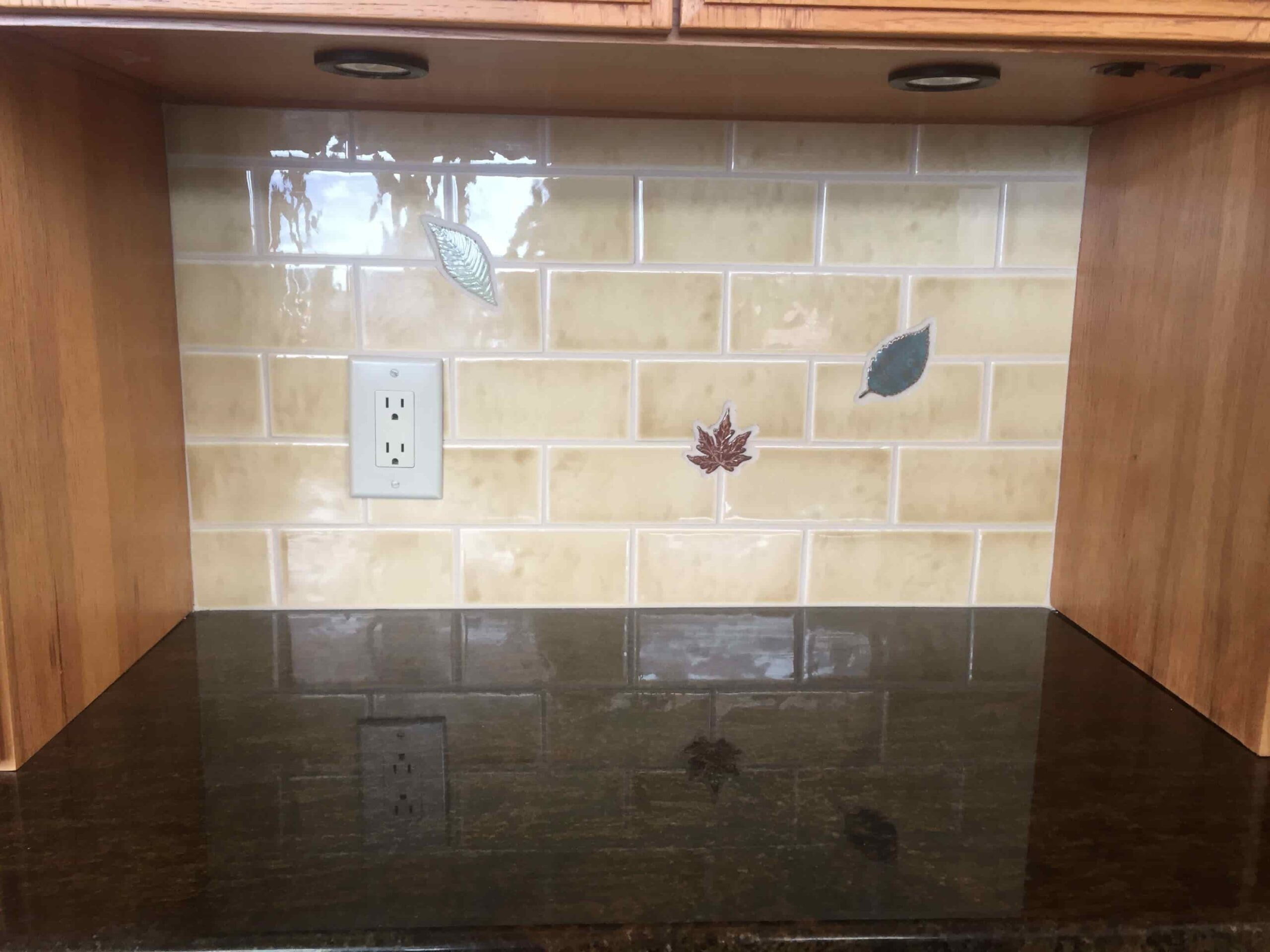 clean, creamy beige subway backsplash tiles with occasional leaf accents adding a personal touch