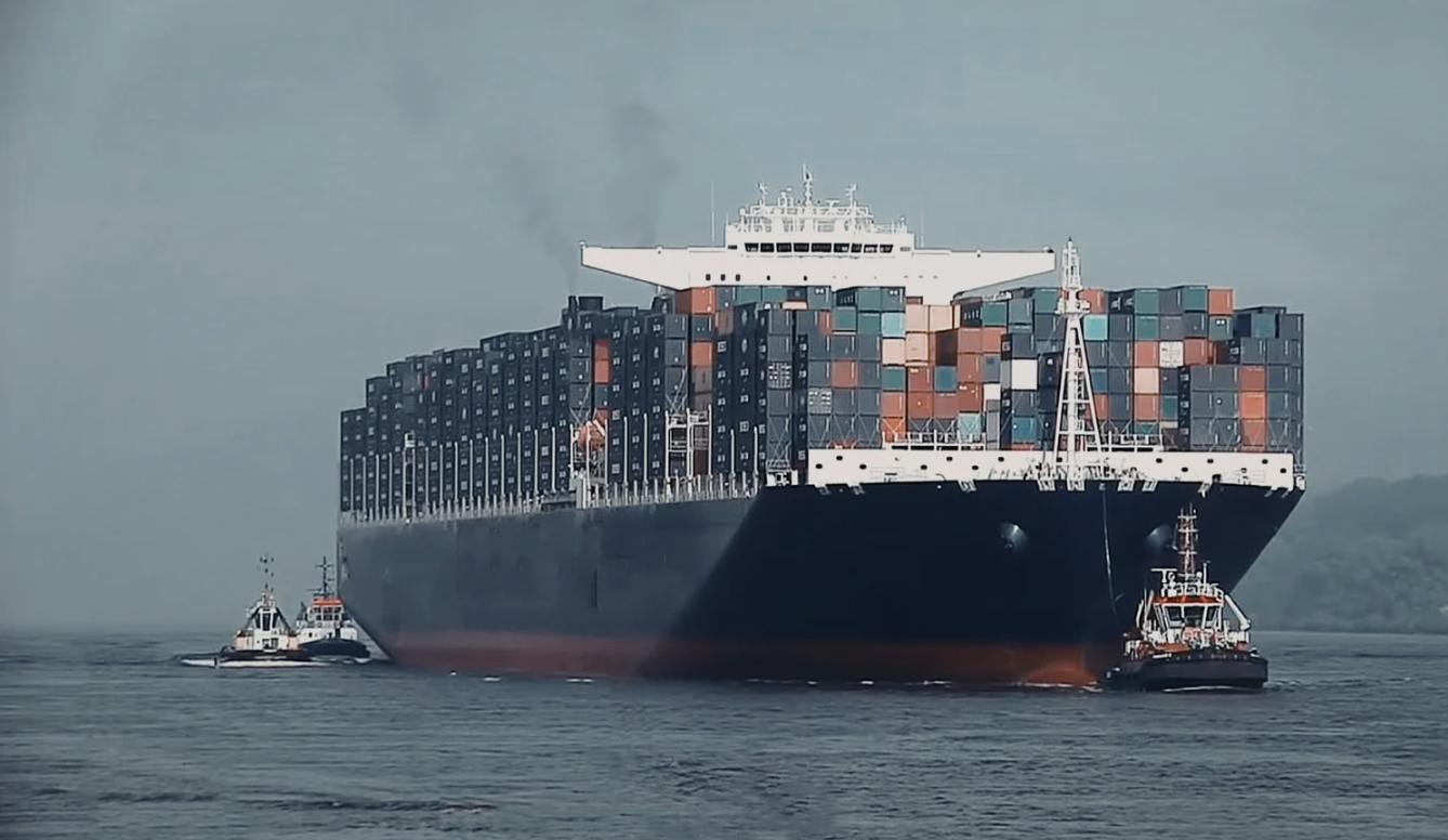 Tugboat pulling large cargo ship.