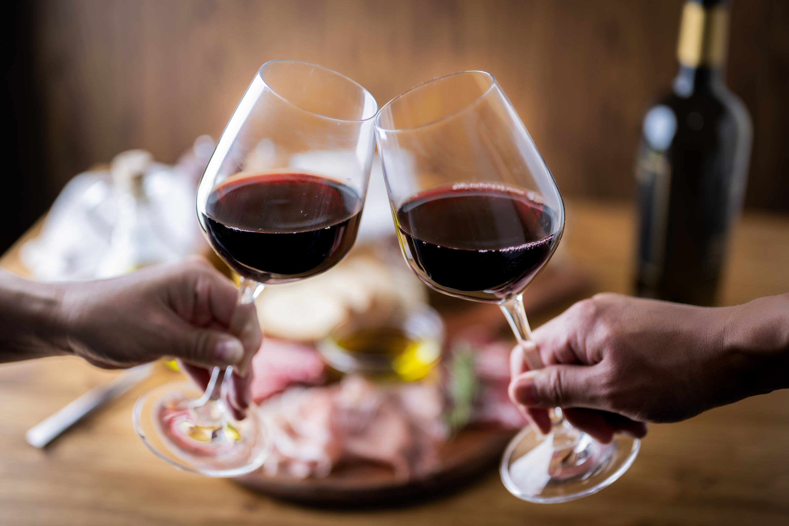 Two people toasting with red wine.