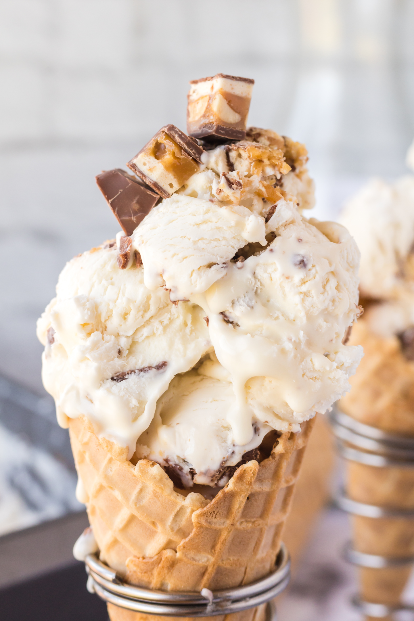 close up of a snickers ice cream in a cone sitting in a cone holder